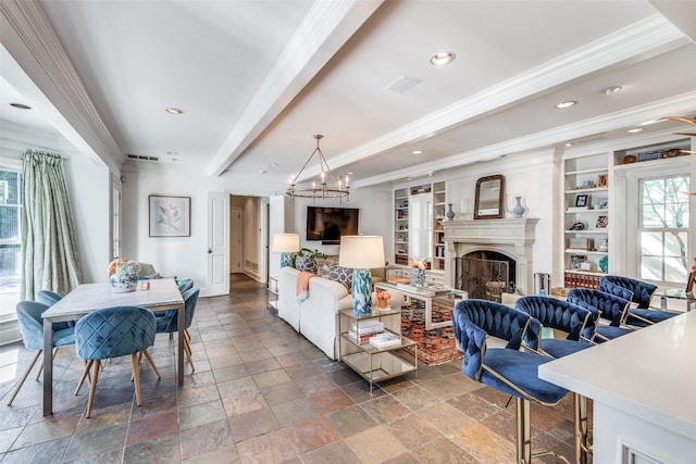 living room with built in shelves, ornamental molding, beam ceiling, and an inviting chandelier