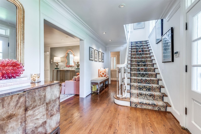 entrance foyer with crown molding, a healthy amount of sunlight, and hardwood / wood-style floors