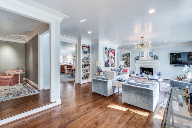 living room with built in shelves, dark hardwood / wood-style floors, an inviting chandelier, and crown molding