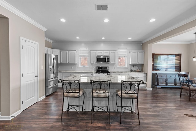 kitchen featuring stainless steel appliances, a kitchen breakfast bar, a center island with sink, and white cabinets