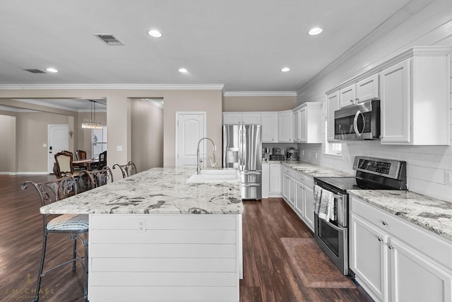 kitchen featuring stainless steel appliances, a kitchen bar, an island with sink, and white cabinets