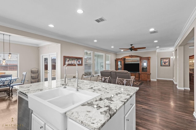 kitchen featuring sink, white cabinetry, dark hardwood / wood-style floors, ornamental molding, and a center island with sink