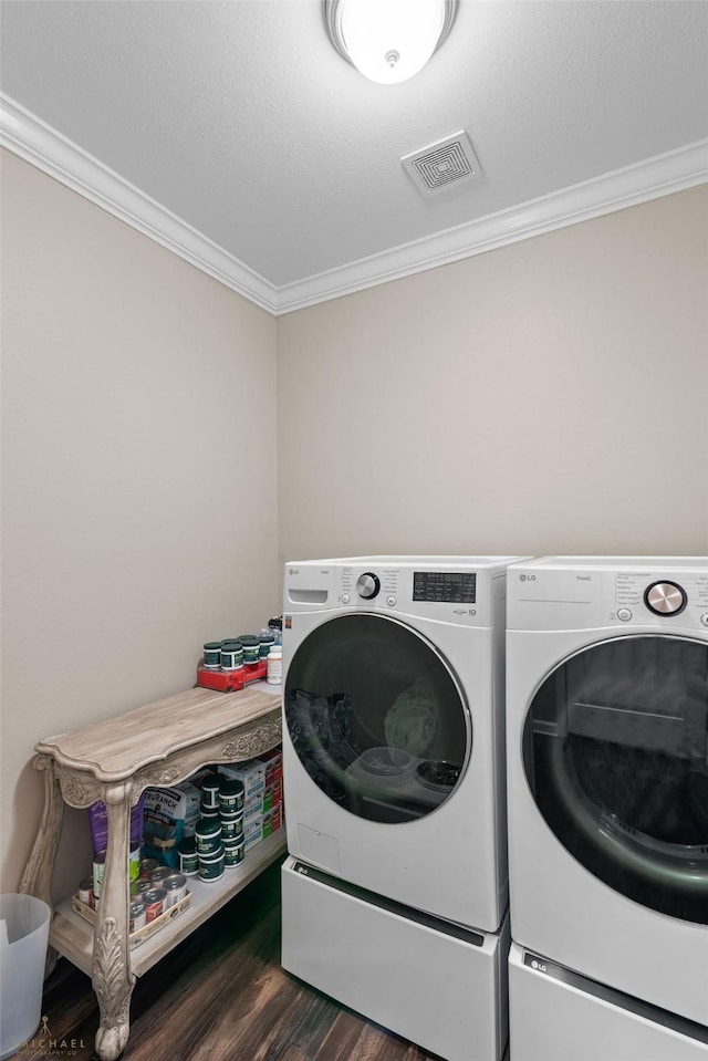 laundry room with dark wood-type flooring, ornamental molding, and washer and dryer