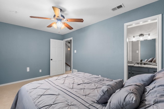 bedroom with ceiling fan, ensuite bathroom, sink, and carpet floors