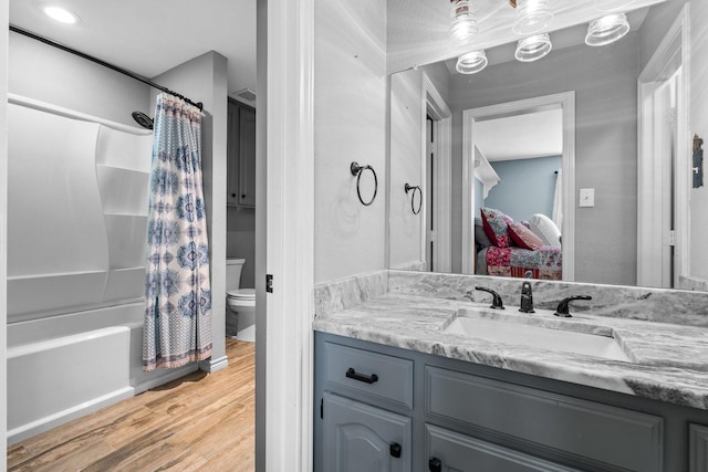 full bathroom with wood-type flooring, vanity, shower / tub combo, and toilet