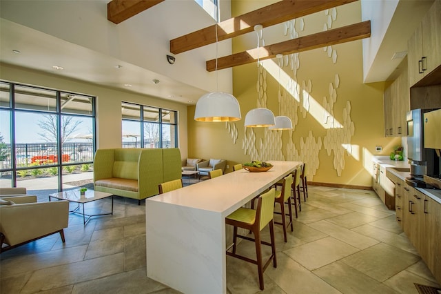 kitchen with pendant lighting, a center island, a high ceiling, a kitchen bar, and beamed ceiling