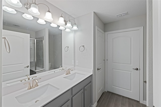 bathroom with vanity, a textured ceiling, a shower with door, and toilet