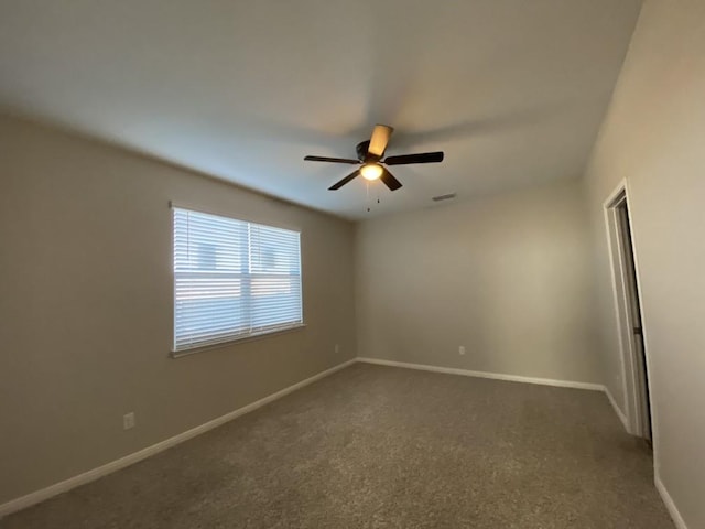 spare room with ceiling fan and dark colored carpet