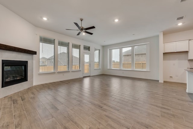 unfurnished living room featuring ceiling fan and a fireplace