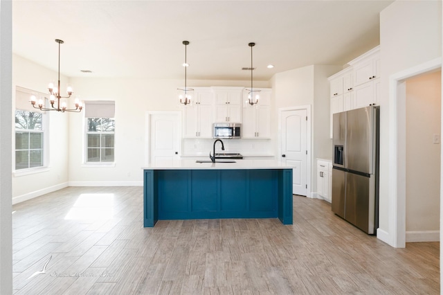 kitchen featuring white cabinetry, appliances with stainless steel finishes, a kitchen island with sink, and pendant lighting