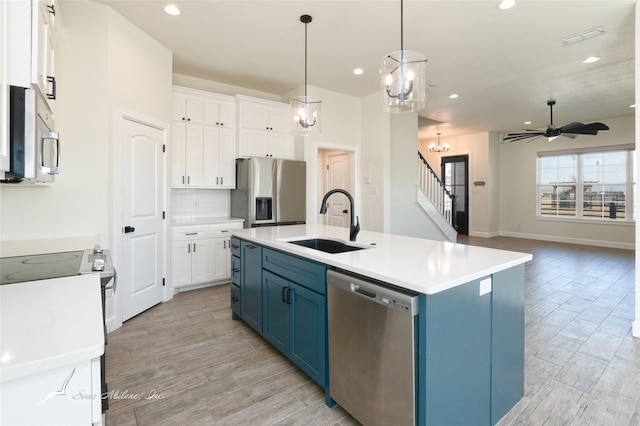 kitchen with blue cabinets, stainless steel appliances, sink, and white cabinets