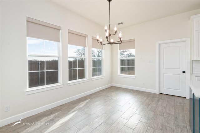 unfurnished dining area with an inviting chandelier and light hardwood / wood-style flooring