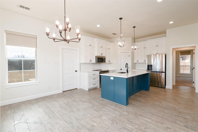 kitchen featuring sink, appliances with stainless steel finishes, decorative light fixtures, and a kitchen island with sink