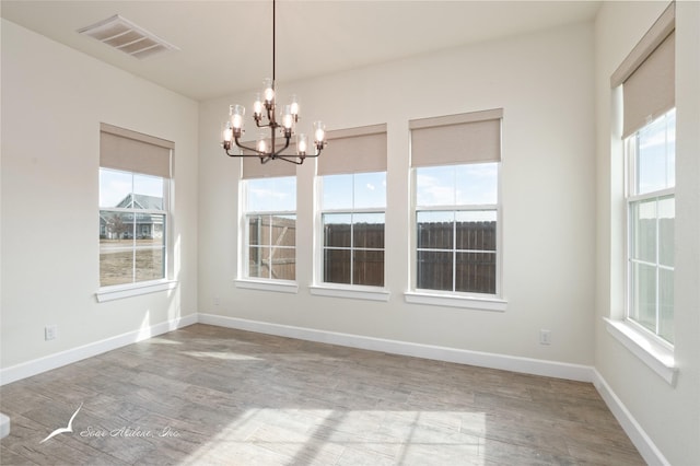 unfurnished dining area featuring a notable chandelier and hardwood / wood-style floors