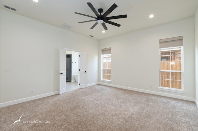 empty room with ceiling fan, light colored carpet, and a healthy amount of sunlight