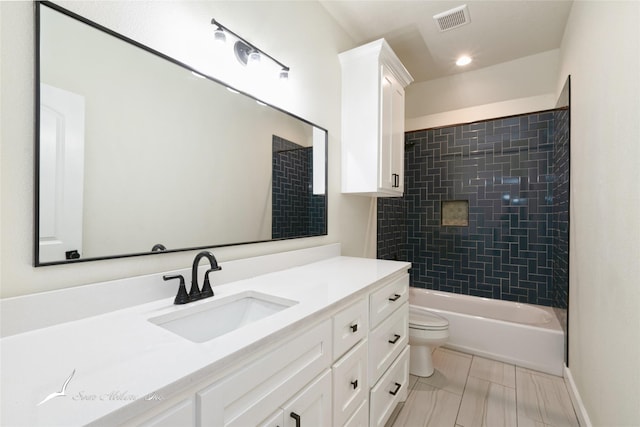 full bathroom featuring tiled shower / bath, vanity, and toilet