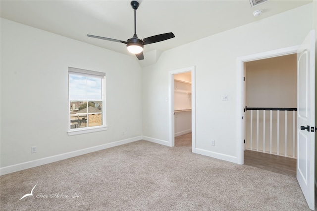 unfurnished bedroom with ceiling fan, a walk in closet, light carpet, and a closet