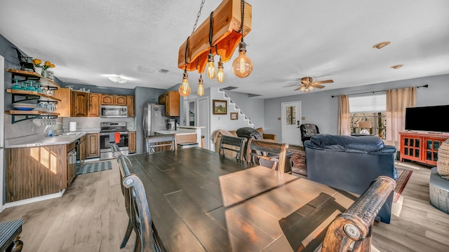 dining space featuring sink, a textured ceiling, light hardwood / wood-style flooring, and ceiling fan