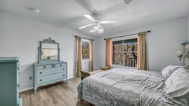 bedroom with ceiling fan, light hardwood / wood-style floors, and a textured ceiling