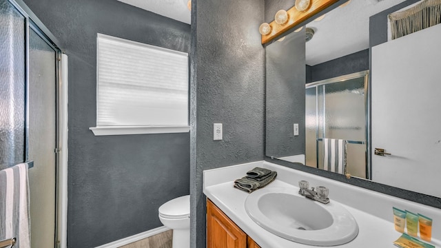 bathroom featuring a shower with door, vanity, hardwood / wood-style flooring, and toilet