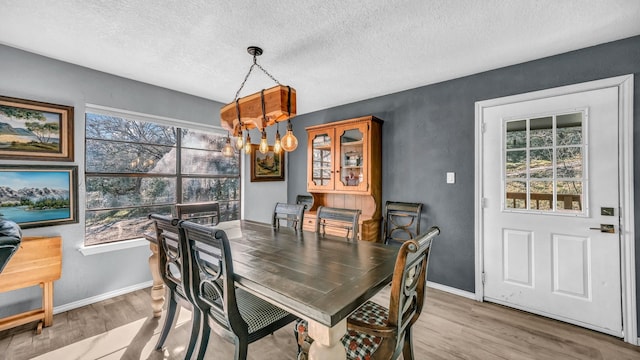 dining area with light hardwood / wood-style floors, a chandelier, and a textured ceiling