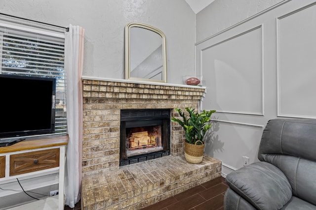 living room featuring a brick fireplace and vaulted ceiling