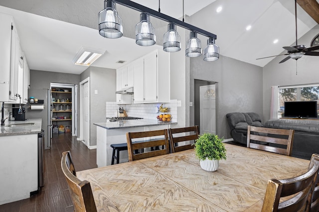 dining room featuring sink, dark wood-type flooring, high vaulted ceiling, and ceiling fan