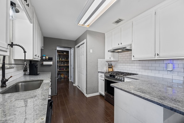 kitchen with dark wood-type flooring, sink, stainless steel range with gas stovetop, light stone countertops, and white cabinets