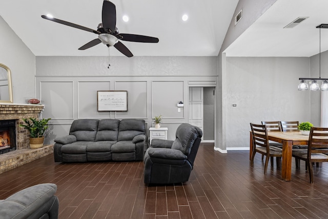 living room featuring lofted ceiling, ceiling fan, and a brick fireplace