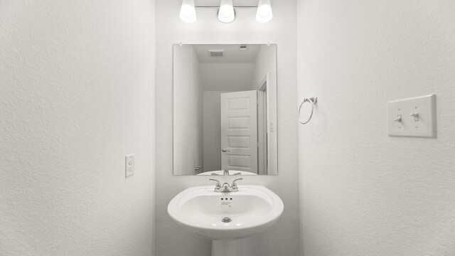 bathroom with a sink, a textured wall, and visible vents