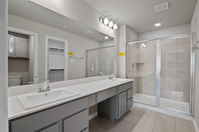 bathroom with tile patterned floors, toilet, a shower with door, and vanity