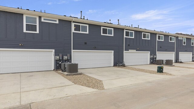 rear view of property featuring central AC unit, board and batten siding, and concrete driveway