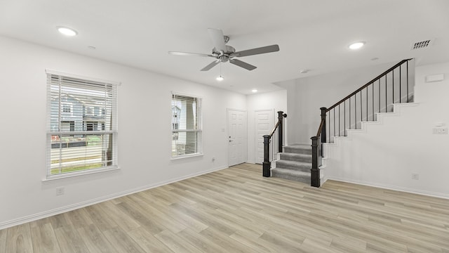 unfurnished living room featuring a ceiling fan, visible vents, stairway, baseboards, and light wood-style flooring