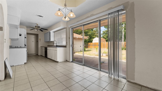 kitchen featuring decorative light fixtures, black dishwasher, white cabinets, light tile patterned floors, and a textured ceiling