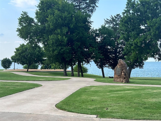 surrounding community with a water view and a lawn