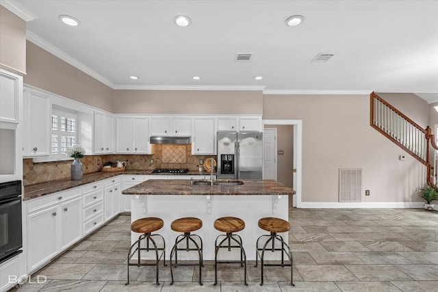 kitchen featuring sink, dark stone countertops, a breakfast bar area, a kitchen island with sink, and stainless steel appliances