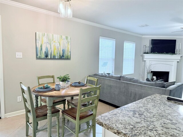 kitchen featuring light tile patterned floors, ornamental molding, appliances with stainless steel finishes, light stone countertops, and white cabinets