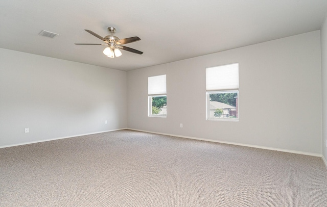 empty room with carpet, visible vents, ceiling fan, and baseboards