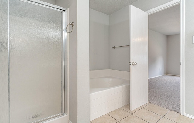 bathroom featuring a textured ceiling, a shower stall, a bath, and tile patterned floors