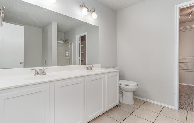 bathroom featuring tile patterned flooring, vanity, a textured ceiling, toilet, and walk in shower