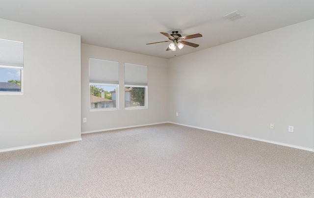 carpeted empty room featuring visible vents, ceiling fan, a wealth of natural light, and baseboards