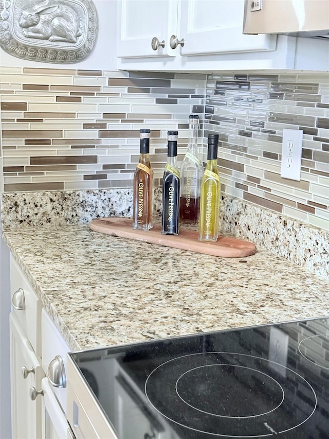 details with white cabinetry, a dry bar, decorative backsplash, and light stone countertops