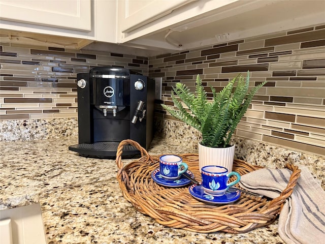 room details with light stone counters, tasteful backsplash, and white cabinets