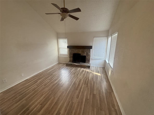 unfurnished living room featuring a fireplace, lofted ceiling, hardwood / wood-style flooring, ceiling fan, and a textured ceiling