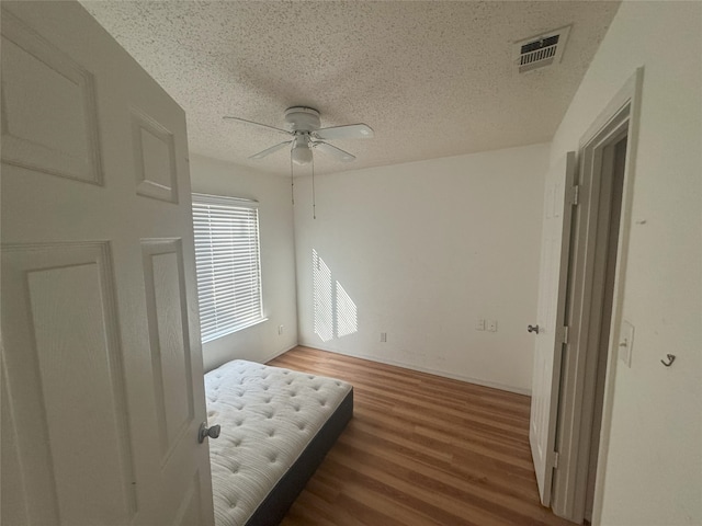 bedroom featuring dark wood-type flooring, a textured ceiling, and ceiling fan