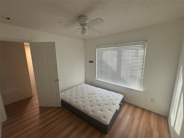 bedroom featuring wood-type flooring, a textured ceiling, and ceiling fan