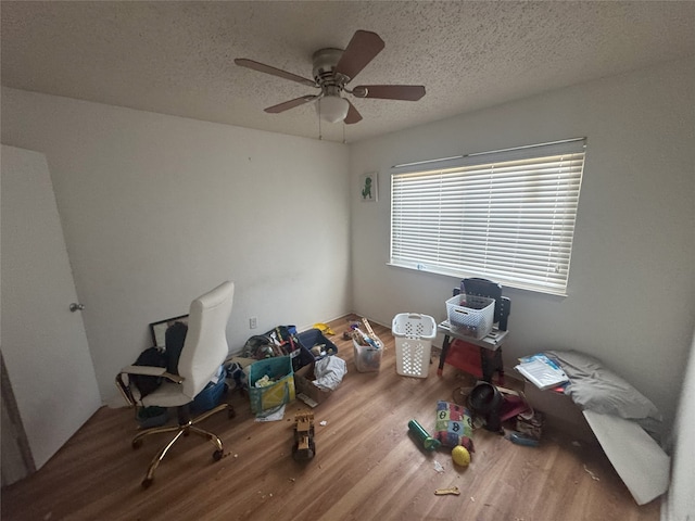 misc room with hardwood / wood-style flooring, ceiling fan, and a textured ceiling