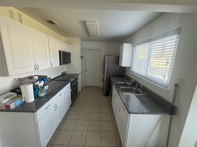 kitchen featuring sink, white cabinetry, light tile patterned floors, stainless steel refrigerator, and electric range