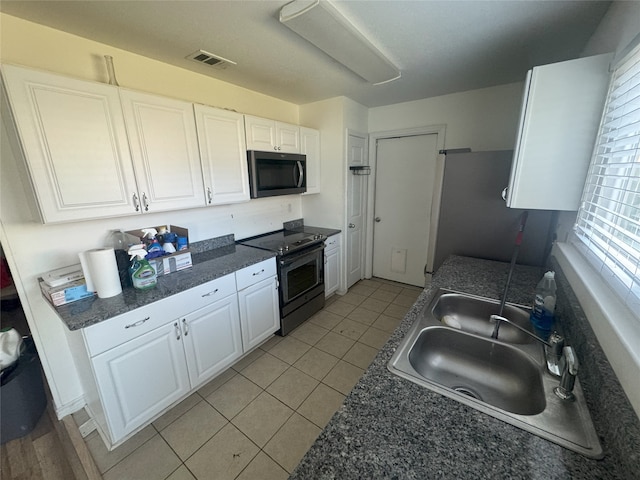 kitchen featuring sink, light tile patterned floors, stainless steel appliances, and white cabinets