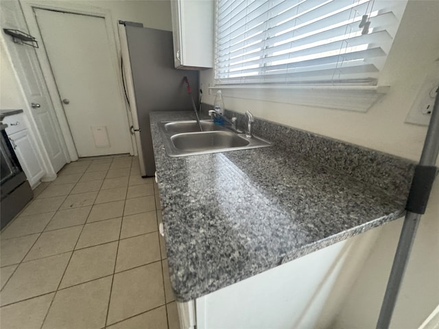 kitchen with white cabinetry, sink, stainless steel fridge, stove, and light tile patterned floors